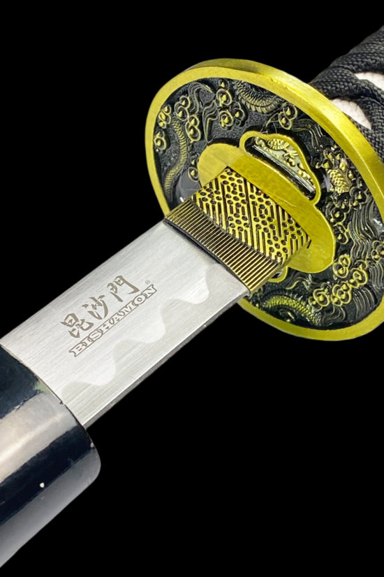 A close-up of the handle of a samurai sword with a black dragon design on the scabbard, featuring an engraved blade and a wooden grip.