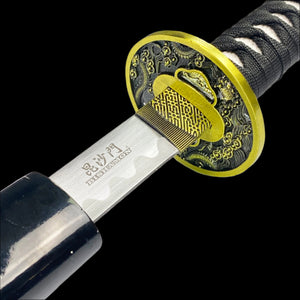 A close-up of the handle of a samurai sword with a black dragon design on the scabbard, featuring an engraved blade and a wooden grip.