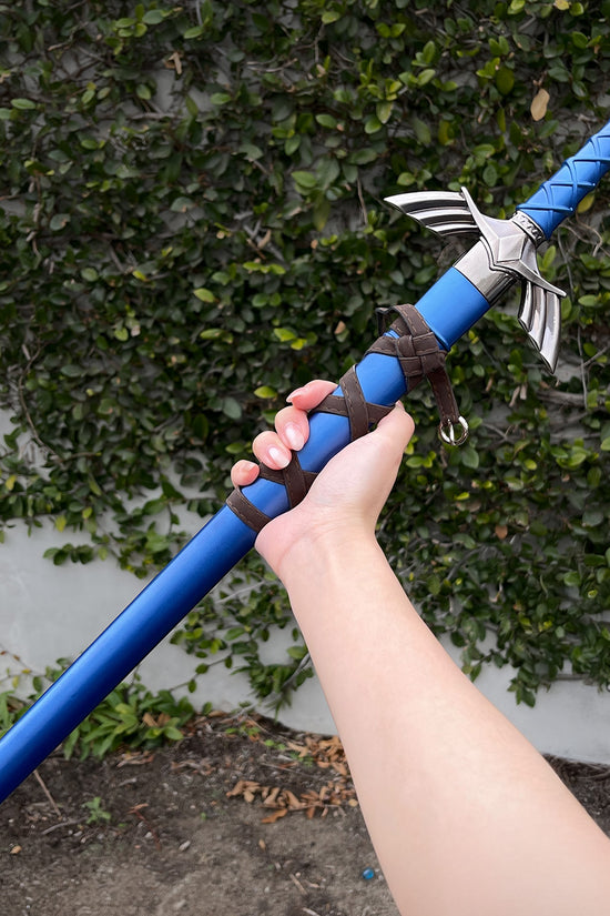Hand holding blue fantasy sword outdoors