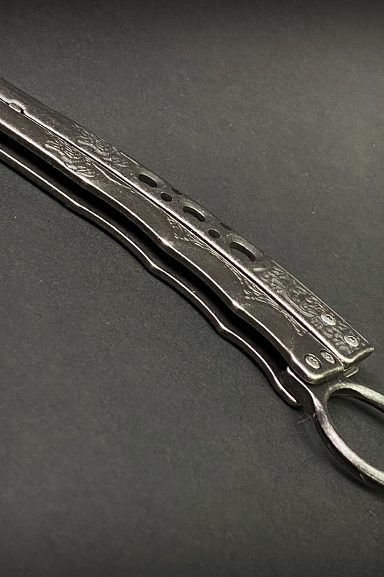 Guild Arms black butterfly trainer knife with detailed handle on dark background