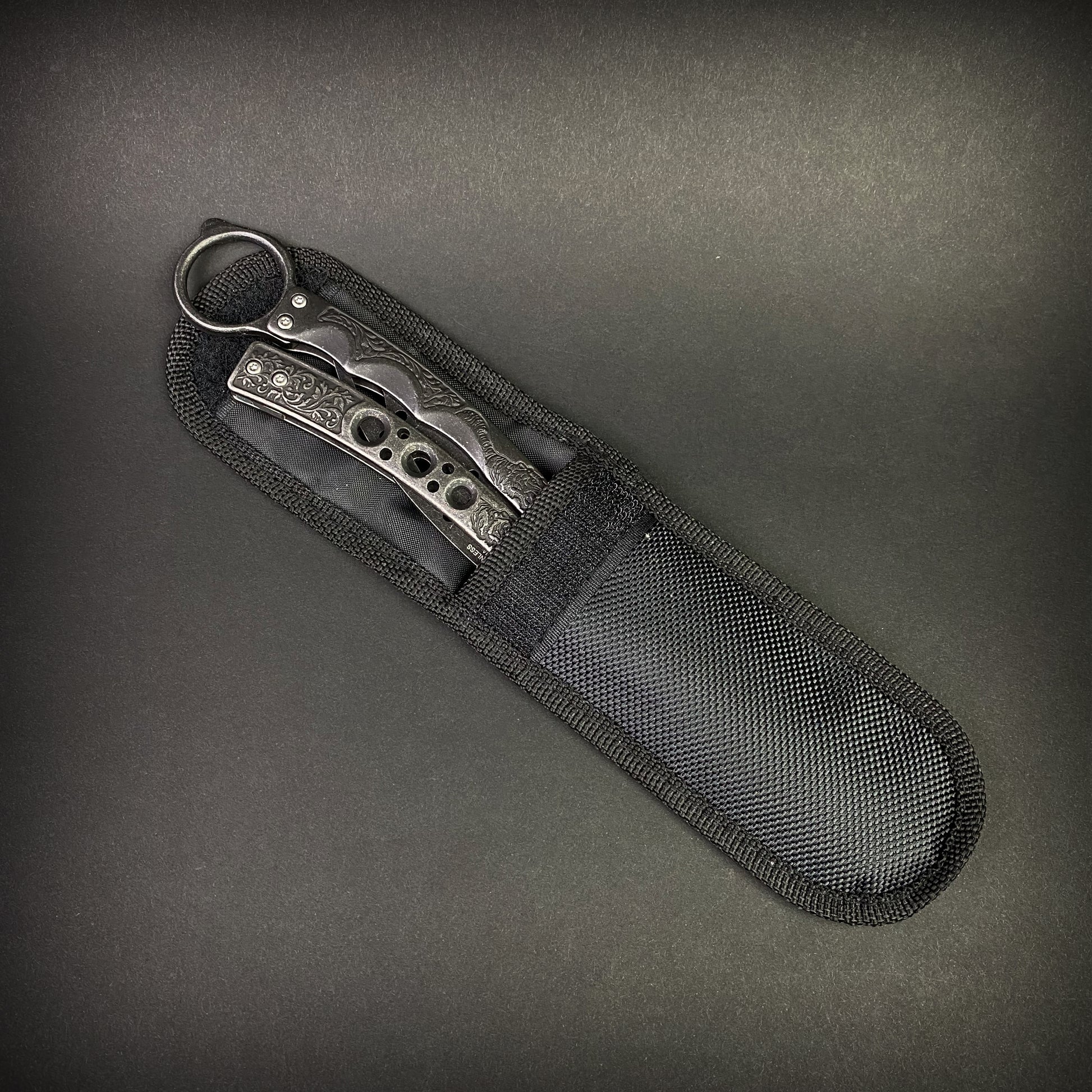 Guild Arms black butterfly trainer knife with textured handles in a black nylon sheath