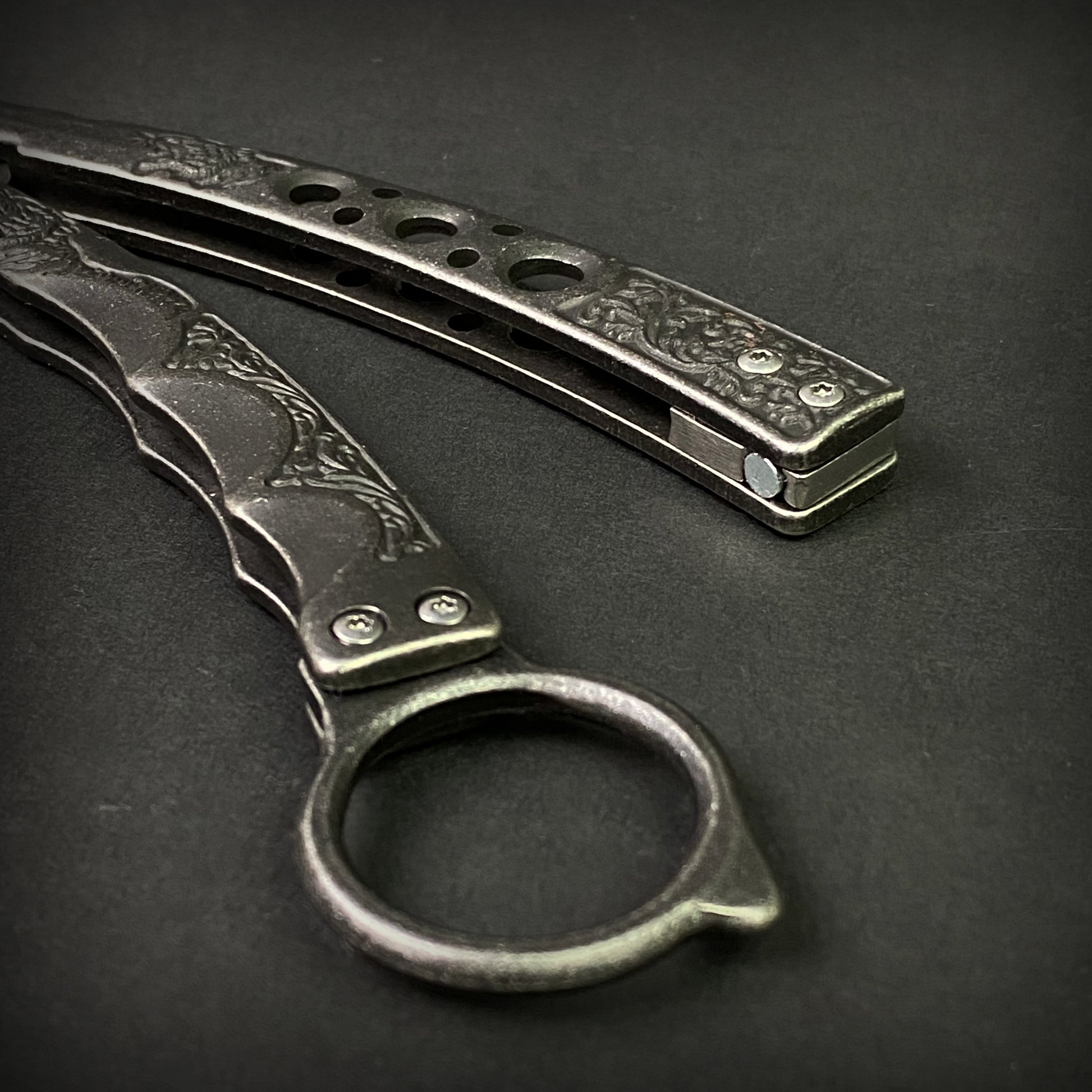 Guild Arms black butterfly trainer knife with detailed engraved metal handles on dark background