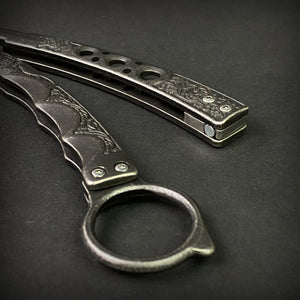 Guild Arms black butterfly trainer knife with detailed engraved metal handles on dark background