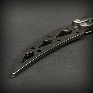 Close-up of Guild Arms black butterfly trainer knife blade with cut-out designs on black background