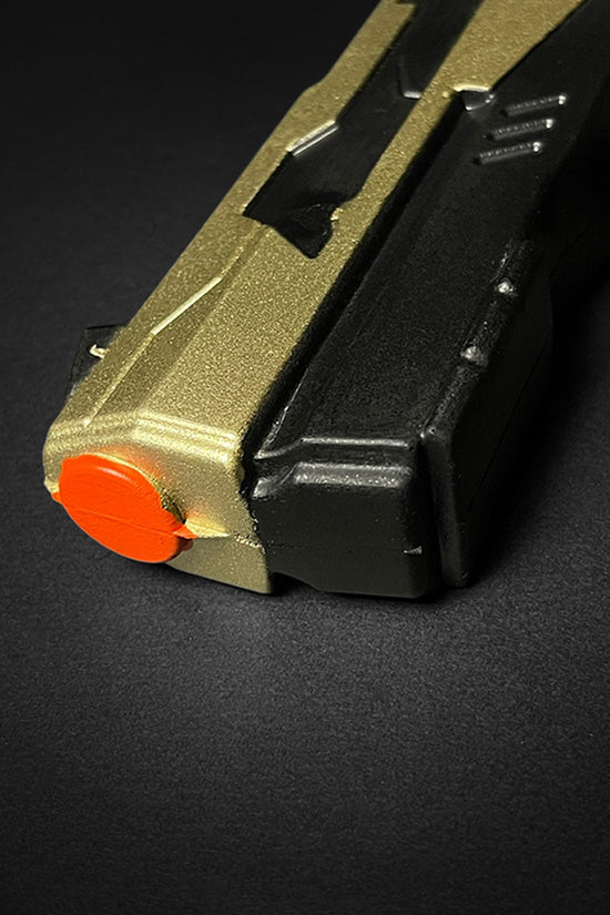 Close-up of Otaku Gear cosplay foam pistol gun with gold and black body and orange tip
