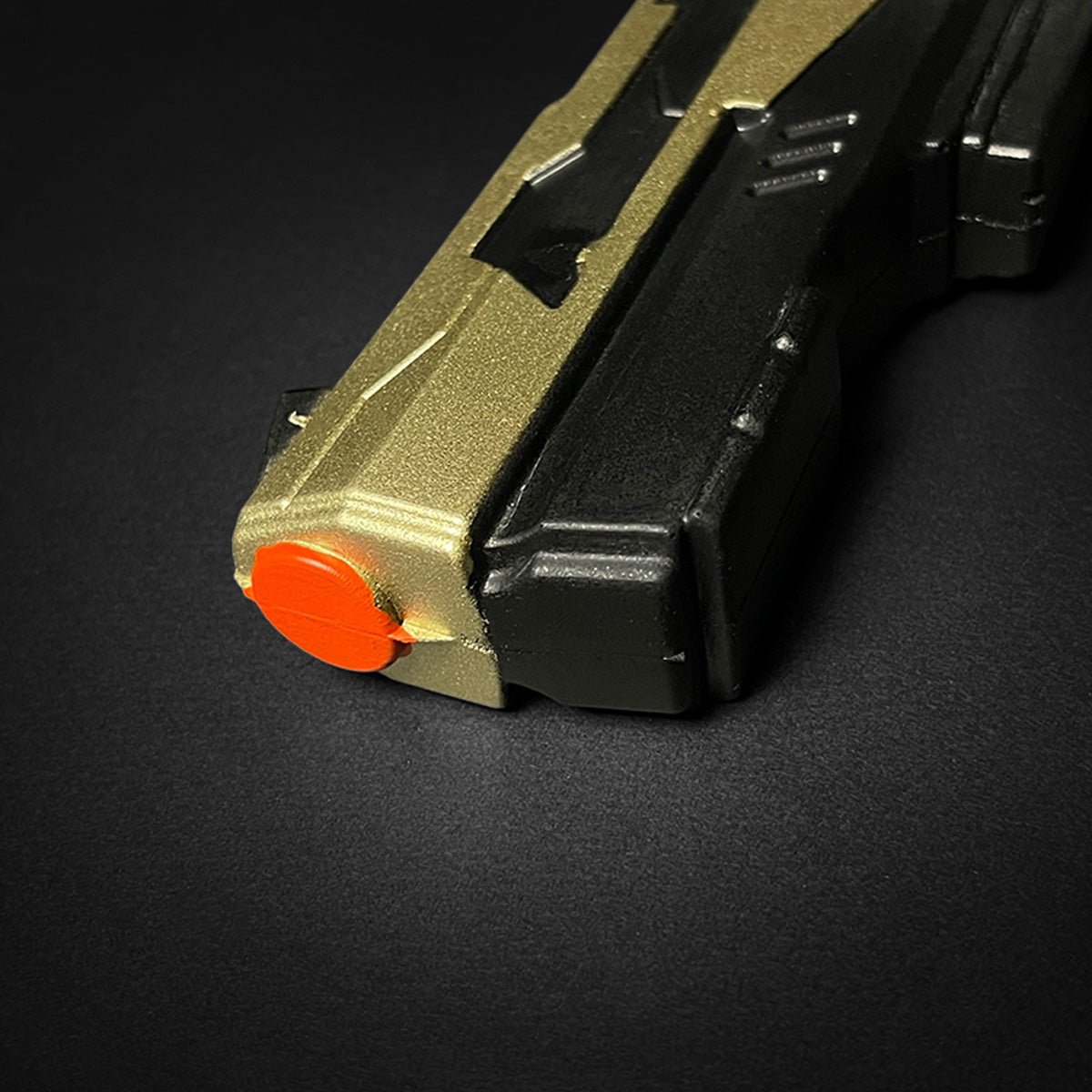 Close-up of Otaku Gear cosplay foam pistol gun with gold and black body and orange tip