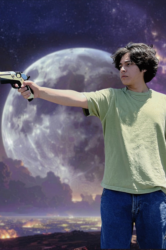 Man holding Otaku Gear cosplay foam pistol gun against a night sky with a large moon background