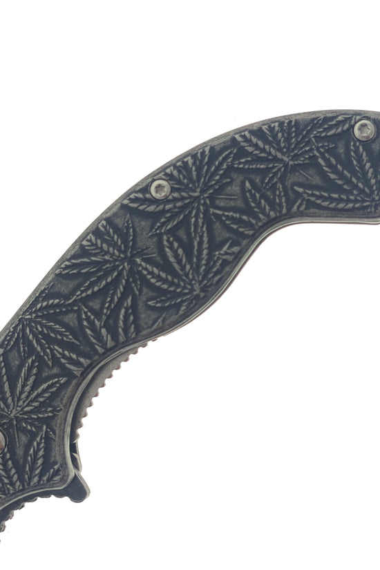 Close up of falcon spring assisted marijuana knife handle showing engraved cannabis leaf pattern and textured grip