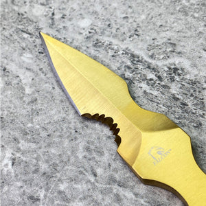 Gold finished falcon tactical knife fixed blade with partial serration and Falcon logo on stone surface