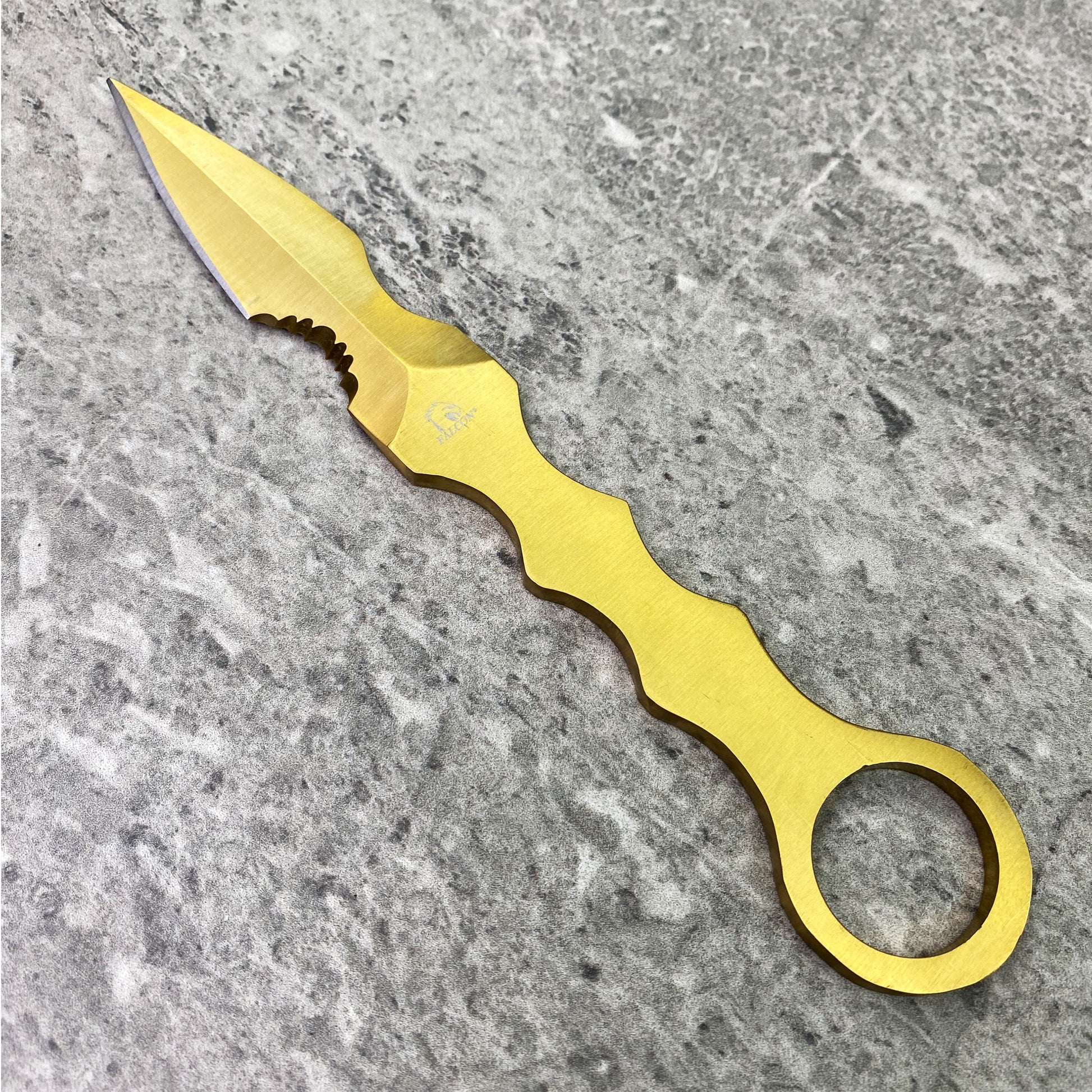 falcon tactical knife fixed blade gold anodized ring handle with ergonomic finger grooves on gray stone background
