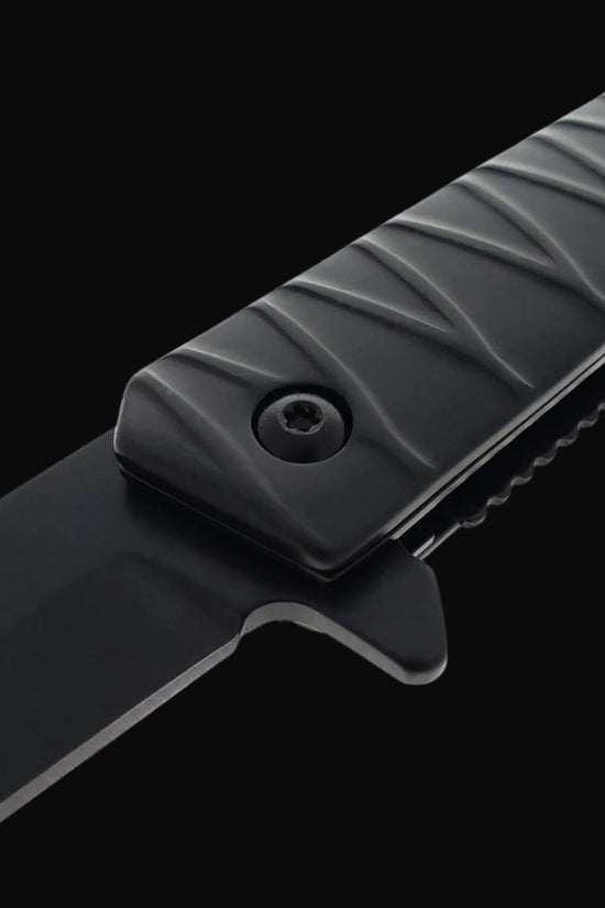 Close up view of Falcon tanto spring assisted pocket knife . black tanto blade and textured ridged handle with logo