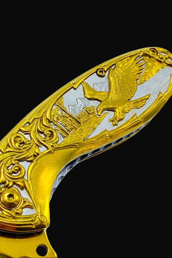 Falcon gold spring assisted knife handle with intricate eagle and scrollwork design