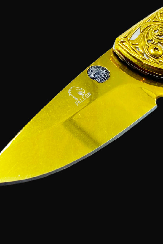 Falcon gold spring assisted knife with ornate engraved handle and sharp blade close-up