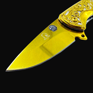 Falcon gold spring assisted knife with ornate engraved handle and sharp blade close-up