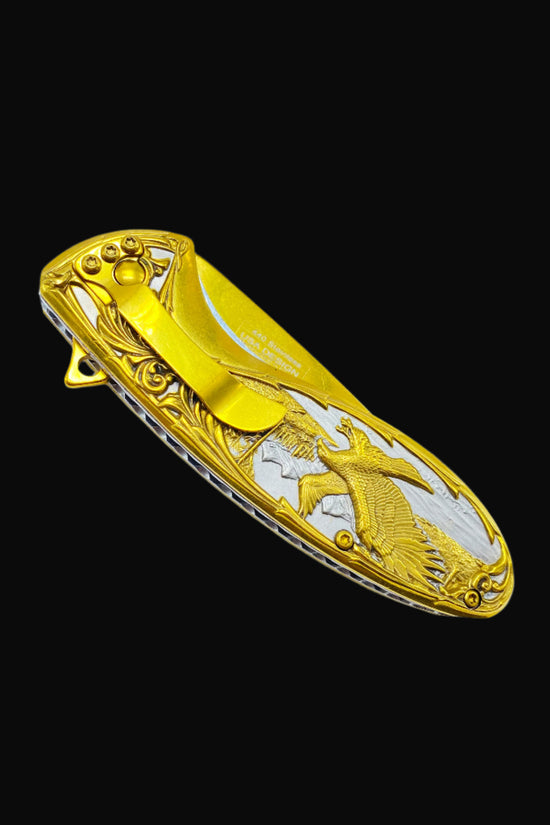 Falcon gold spring assisted knife with detailed eagle design and pocket clip on black background