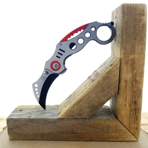 Falcon Red Karambit Spring Assisted Knife displayed on a wooden block for ergonomic design showcase