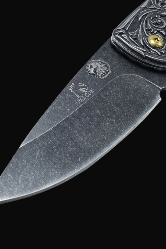 Close-up of Guild Arms spring assisted falcon knife blade with engraved falcon logo and detailed handle