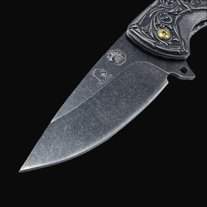 Close-up of Guild Arms spring assisted falcon knife blade with engraved falcon logo and detailed handle