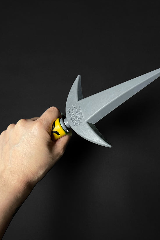 Hand holding Otaku Gears foam flying thunder kunai foam dagger with pointed gray blade and yellow handle