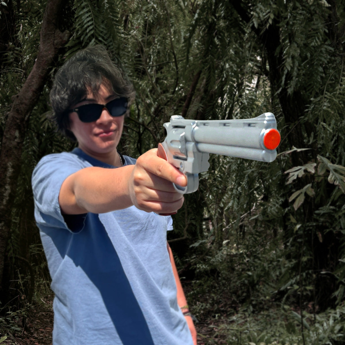 Guild Arms anime foam gun held by person in blue shirt and sunglasses pointing foam revolver prop for cosplay in forest