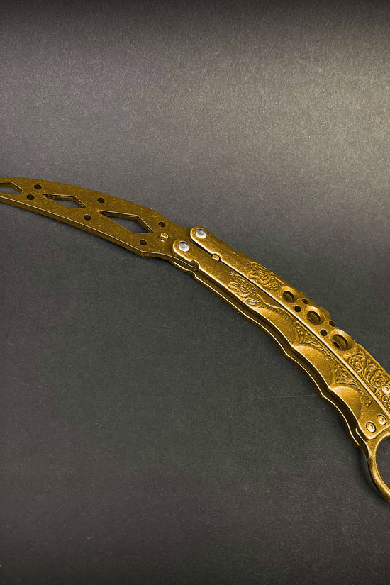 Guild Arms gold butterfly trainer knife with intricate handle and perforated blade for safe flipping practice