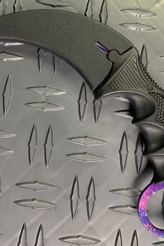 Falcon purple karambit trainer knife with curved black blade and galaxy-patterned handle ring