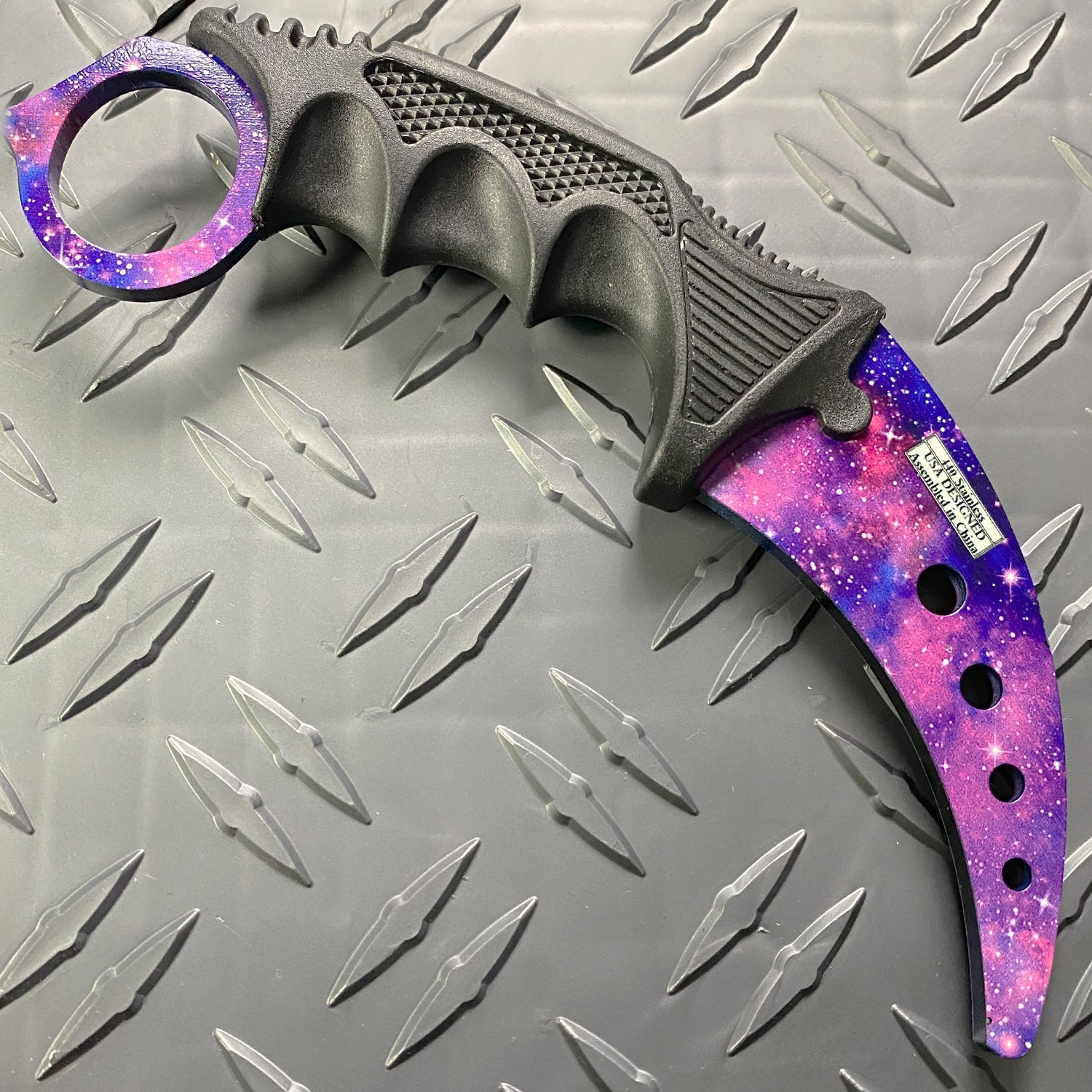 Falcon purple karambit trainer knife with galaxy design and textured black grip on metal background